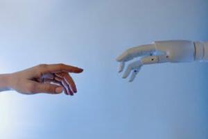 embracing AI, a human hand and a robot reaching out